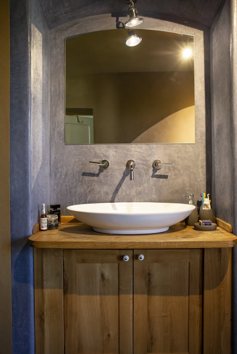 Dubový stolek pod umyvadlem a marocký štuk na stěnách.