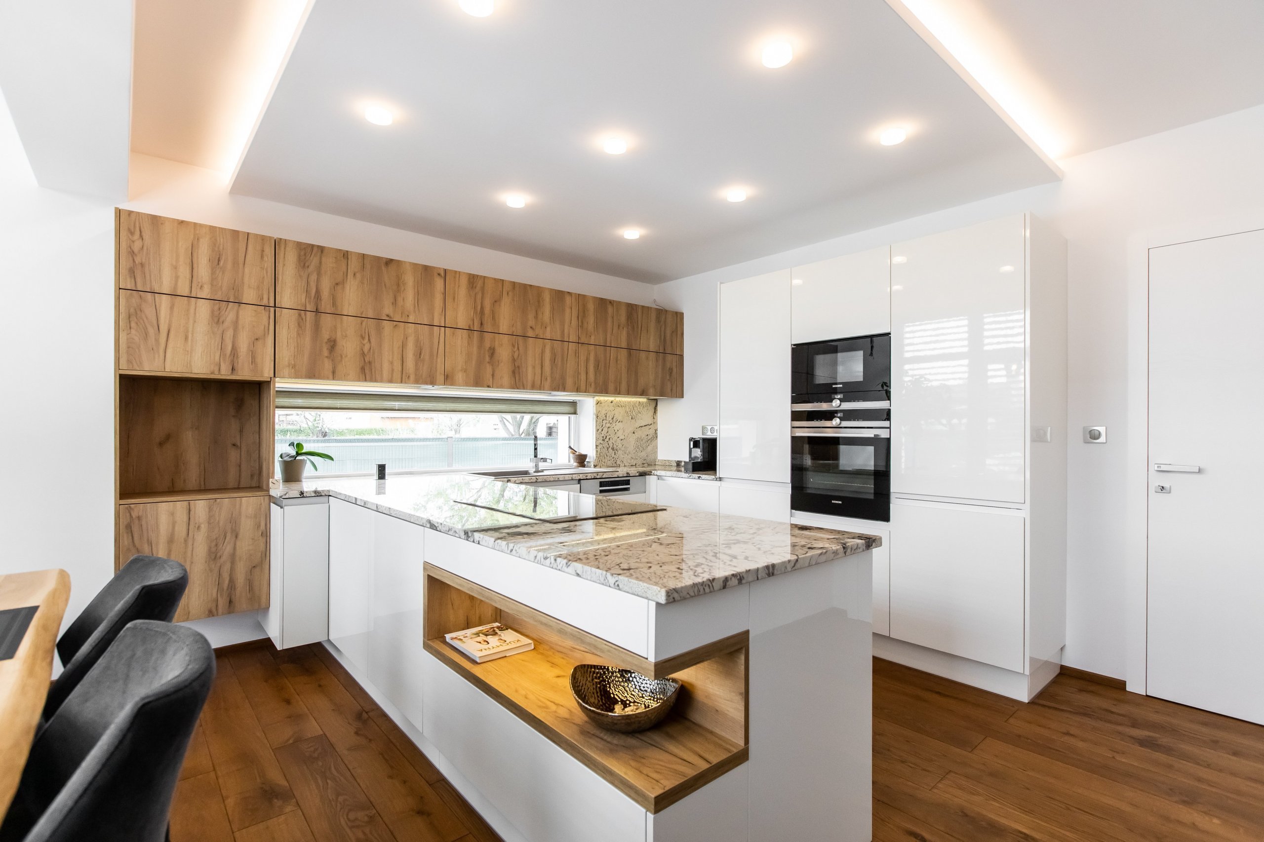 Použité materiály
Horné skrinky: Dub zlatý
Dolné skrinky: Biely akryl vo vysokom lesku
Vysoké skrinky: Biely akryl vo vysokom lesku
Zástena a pracovná…