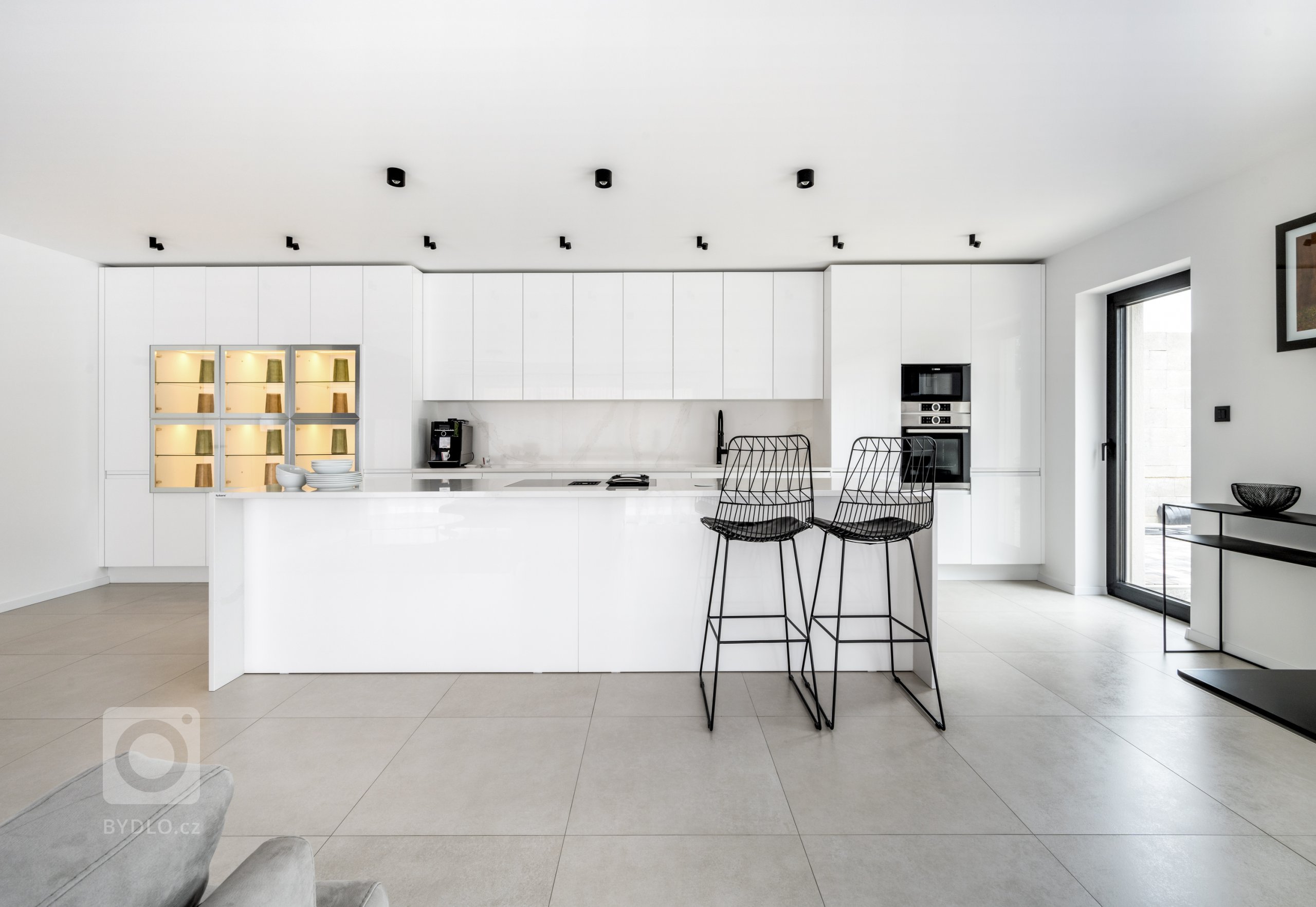 Sestava v hladkém, čistém designu Pure tvoří celou jednu stranu místnosti.
Geometricky vyrovnaná a přesto členitá, designová a zároveň praktická, nabízí ideální podmínky pro kulinářské aktivity i pro rodinný život. Bílé dvířka skříněk jsou lakované v lesku White, který se snadno udržuje a odolává stopám času i rodinných příslušníků. 
