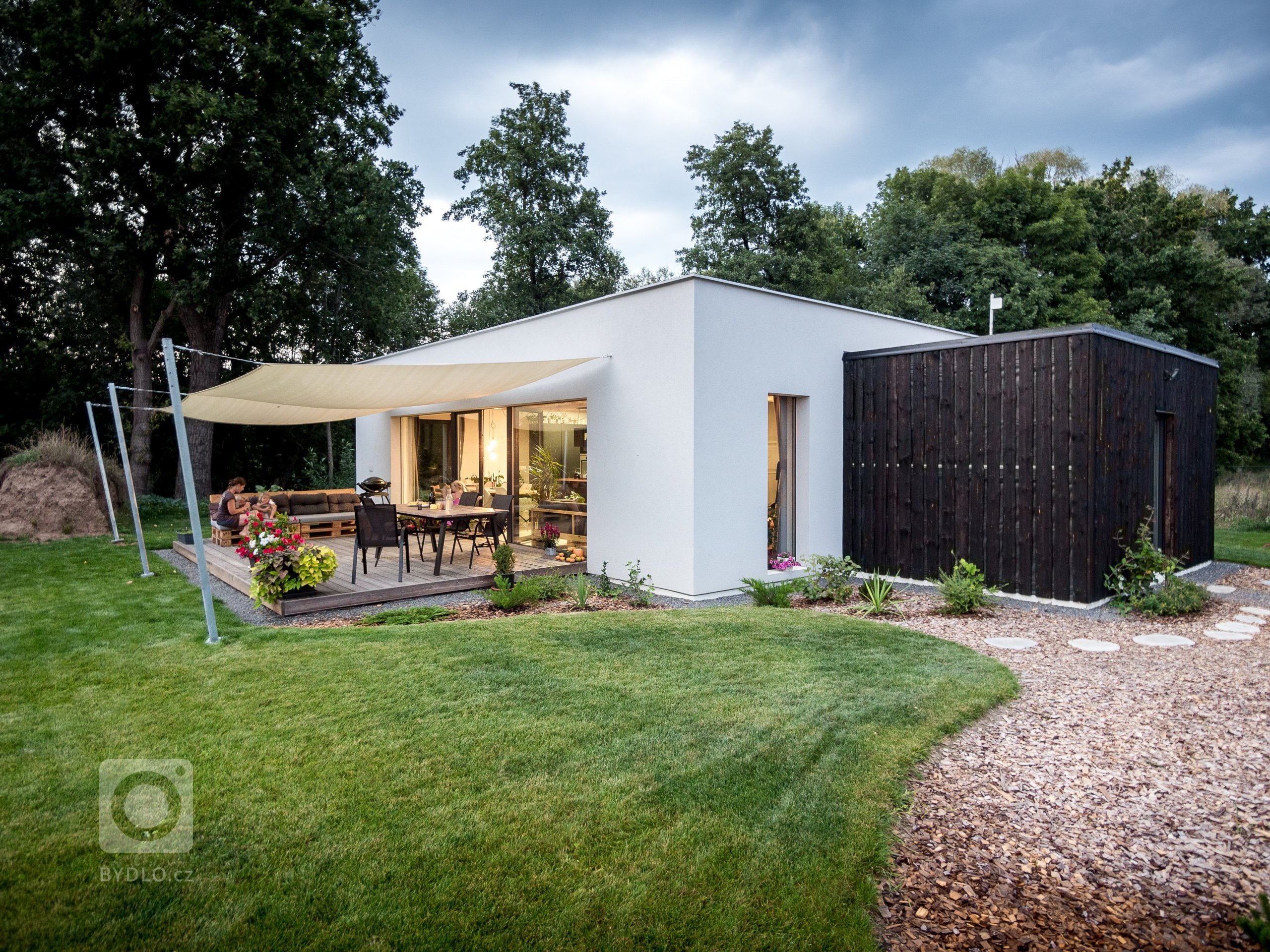 Základní hmotu domu ZEN HOME doplňuje přístavba z černých nesámovaných prken a výrazné textilní stínění terasy.